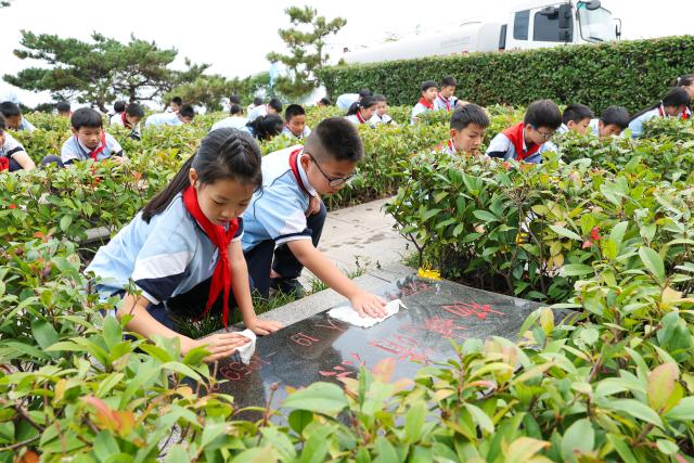 (260930) -- BEIJING, Sept. 30, 2026 (Xinhua) -- Students clean martyrs' graves at a martyrs' cemetery in Lianyungang City, east China's Jiangsu Province, Sept. 29, 2026. Commemorative events were held across China to mark Martyrs' Day in recent days. Observed on Sept. 30, one day before National Day, the day commemorates those who gave their lives for national independence and prosperity. (Photo by Wang Jianmin/Xinhua)