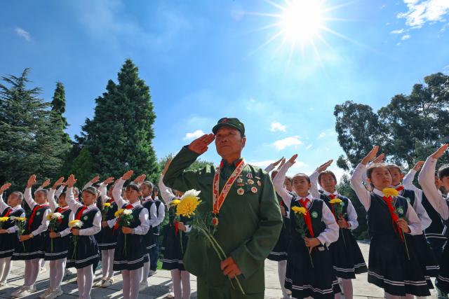 (260930) -- BEIJING, Sept. 30, 2026 (Xinhua) -- A veteran and students salute to martyrs' sculptures at a martyrs' cemetery in Qujing City, southwest China's Yunnan Province, Sept. 30, 2026. Commemorative events were held across China to mark Martyrs' Day in recent days. Observed on Sept. 30, one day before National Day, the day commemorates those who gave their lives for national independence and prosperity. (Photo by Wang Yong/Xinhua)