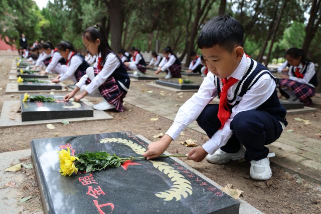 (260930) -- BEIJING, Sept. 30, 2026 (Xinhua) -- Students present flowers to martyrs at a martyrs' cemetery in Binzhou City, east China's Shandong Province, Sept. 30, 2026. Commemorative events were held across China to mark Martyrs' Day in recent days. Observed on Sept. 30, one day before National Day, the day commemorates those who gave their lives for national independence and prosperity. (Photo by Jia Haining/Xinhua)