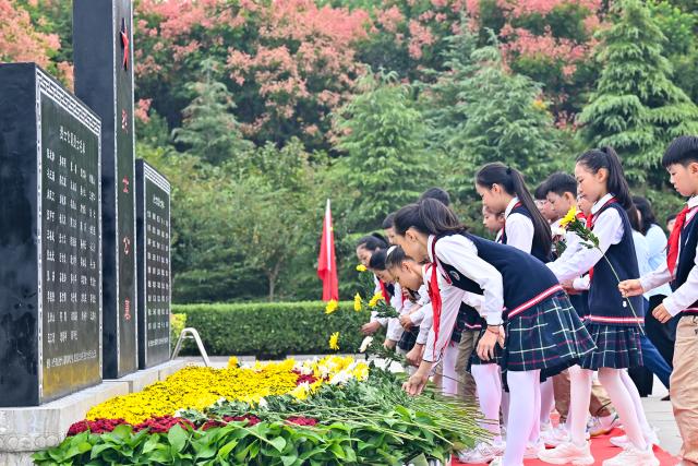 (260930) -- BEIJING, Sept. 30, 2026 (Xinhua) -- Students present flowers to martyrs at a martyrs' cemetery in Shangqiu City, central China's Henan Province, Sept. 30, 2026. Commemorative events were held across China to mark Martyrs' Day in recent days. Observed on Sept. 30, one day before National Day, the day commemorates those who gave their lives for national independence and prosperity. (Photo by Li Heng/Xinhua)