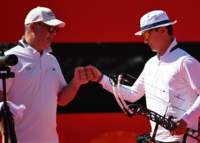 (261001) -- OKAZAKI, Oct. 1, 2026 (Xinhua) -- Kim Jongho (R) of South Korea and his coach Sergio Pagni bump fists during the compound men's individual quarterfinals of archery against Liao Jiahao of China at the 20th Asian Games Aichi-Nagoya 2026 in Okazaki of Aichi Prefecture, Japan, Oct. 1, 2026. (Xinhua/Yu Yang)