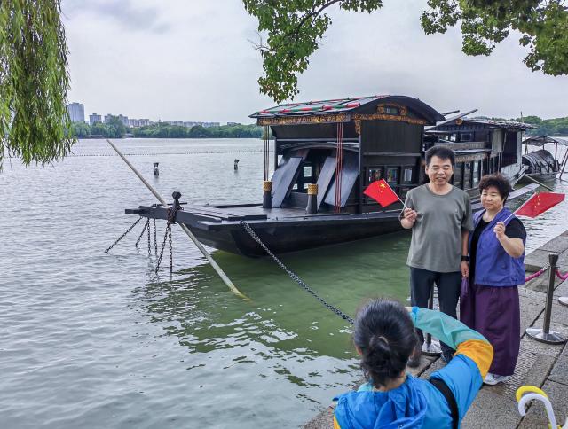 (261001) -- BEIJING, Oct. 1, 2026 (Xinhua) -- Tourists pose for a photo at the Nanhu Lake scenic area in Jiaxing, east China's Zhejiang Province, Oct. 1, 2026. People celebrated the 77th anniversary of the founding of the People's Republic of China in various ways on Thursday. (Xinhua/Xu Yu)