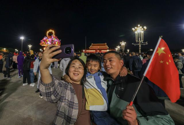 (261001) -- BEIJING, Oct. 1, 2026 (Xinhua) -- Visitors take a selfie at Tian'anmen Square in Beijing, capital of China, Oct. 1, 2026. People celebrated the 77th anniversary of the founding of the People's Republic of China in various ways on Thursday. (Xinhua/Yin Gang)