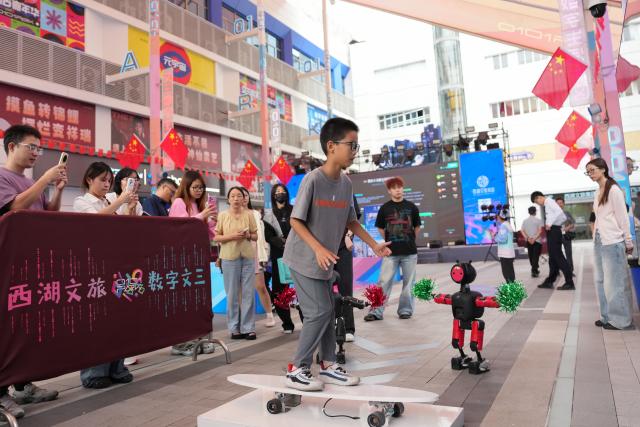 (261001) -- HANGZHOU, Oct. 1, 2026 (Xinhua) -- A child experiences digital surfing activities at a digital lifestyle block in Hangzhou, east China's Zhejiang Province, Oct. 1, 2026. A series of activities featuring human-robot interaction is held here from Oct. 1 to 3. (Xinhua/Huang Zongzhi)