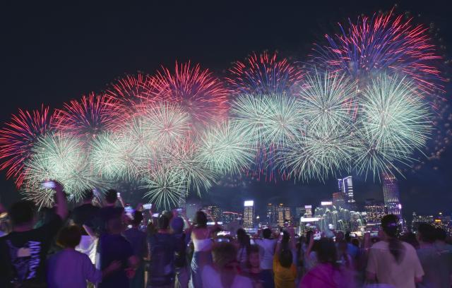 (261001) -- HONG KONG, Oct. 1, 2026 (Xinhua) -- Tourists watch the firework show celebrating the 77th anniversary of the founding of the People's Republic of China in Hong Kong, south China, Oct. 1, 2026. People across China stepped out to fully enjoy their leisure time during the National Day holiday. (Xinhua/Chen Duo)