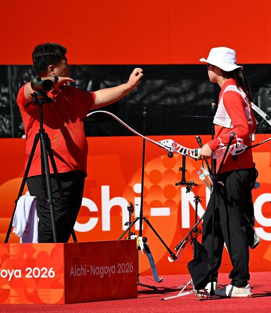 (261002) -- OKAZAKI, Oct. 2, 2026 (Xinhua) -- Zhu Jingyi (R) of team China communicates with her coach during the recurve women's team bronze medal match of archery against team Indonesia at the 20th Asian Games Aichi-Nagoya 2026 in Okazaki of Aichi Prefecture, Japan, Oct. 2, 2026. (Xinhua/Yu Yang)
