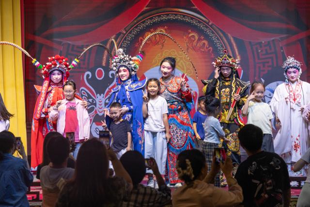 (261002) -- BEIJING, Oct. 2, 2026 (Xinhua) -- Tourists pose for photos with Sichuan Opera performers at a theater in Yibin City, southwest China's Sichuan Province, Oct. 1, 2026. During the National Day holiday, various cultural and tourism events are held across the country to attract visitors. (Photo by Peng Minxiang/Xinhua)