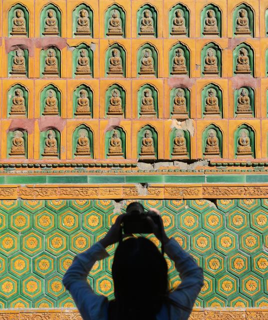 (261002) -- BEIJING, Oct. 2, 2026 (Xinhua) -- A visitor takes photos of a colored glazed pavilion courtyard which is open to public after 70 years of being sealed off at Beihai Park in Beijing, capital of China, Oct. 1, 2026. During the National Day holiday, various cultural and tourism events are held across the country to attract visitors. (Photo by Wang Yuewu/Xinhua)