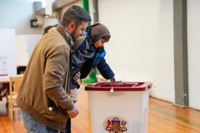 (261003) -- RIGA, Oct. 3, 2026 (Xinhua) -- A voter casts a ballot with his child at a polling station in Riga, Latvia, Oct. 3, 2026.
  Voting in the Latvian parliamentary election began on Saturday morning, with 1,428 candidates vying for 100 seats in the 15th Saeima, Latvia's parliament. (Photo by Edijs Palens/Xinhua)