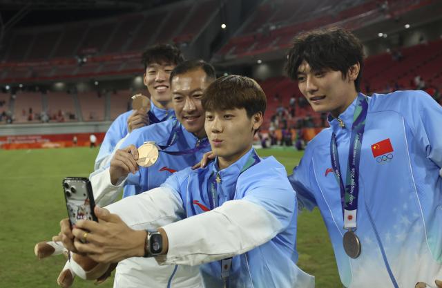 (261003) -- TOYOTA, Oct. 3, 2026 (Xinhua) -- Players of team China pose for photos after the awarding ceremony for men's football event at 20th Asian Games Aichi-Nagoya 2026 in Toyota of Aichi Prefecture, Japan, Oct. 3, 2026. (Xinhua/Jia Haocheng)