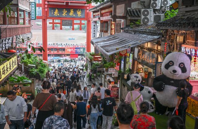 (261003) -- BEIJING, Oct. 3, 2026 (Xinhua) -- Tourists visit the Ciqikou ancient town in southwest China's Chongqing Municipality on Oct. 3, 2026.
  China's cultural and tourism market is thriving during this year's National Day holiday, with a wide range of options including scenic getaways, autumn outings, tourism with revolutionary topics, nighttime entertainment, and cultural tours featuring the country's intangible cultural heritage. (Xinhua/Chen Cheng)