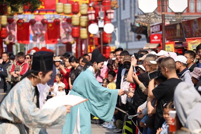 (261004) -- BEIJING, Oct. 4, 2026 (Xinhua) -- Tourists interact with actors at Yangliuqing ancient town in Tianjin, north China, Oct. 3, 2026.
  China's cultural and tourism market is thriving during this year's National Day holiday, with a wide range of options including scenic getaways, autumn outings, tourism with revolutionary topics, nighttime entertainment, and cultural tours featuring the country's intangible cultural heritage. (Xinhua/Li Ran)