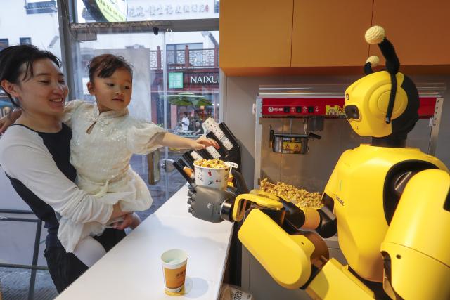 (261004) -- HEFEI, Oct. 4, 2026 (Xinhua) -- A robot makes popcorn at a store in Tunxi District of Huangshan, east China's Anhui Province, Oct. 1, 2026. During the National Day holiday, embodied AI robots of various functions rolled out in commercial and cultural blocks have been a major attraction for tourists. Through smart interactions, they have diversified tourism offerings and experiences. (Photo by Shi Yalei/Xinhua)