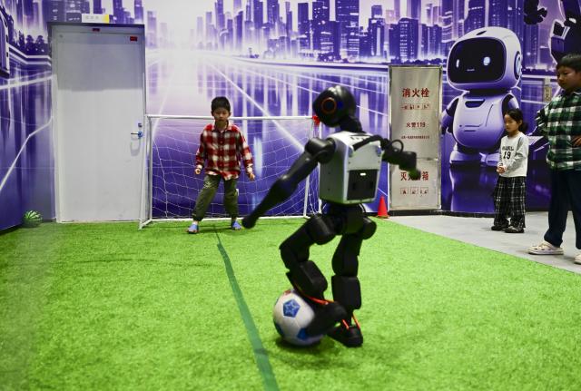 (261004) -- HEFEI, Oct. 4, 2026 (Xinhua) -- A robot plays football with a boy in a public venue in Hefei, east China's Anhui Province, Oct. 3, 2026. During the National Day holiday, embodied AI robots of various functions rolled out in commercial and cultural blocks have been a major attraction for tourists. Through smart interactions, they have diversified tourism offerings and experiences. (Xinhua/Zhou Mu)