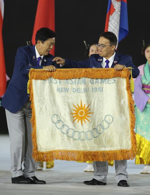 (261004) -- NAGOYA, Oct. 4, 2026 (Xinhua) -- Ohmura Hideaki (R), President of the Aichi-Nagoya Asian Games and Asian Para Games Organizing Committee, holds the flag of the first Asian Games New Delhi 1951 during the closing ceremony of the 20th Asian Games Aichi-Nagoya 2026 in Nagoya, Japan, Oct. 4, 2026. (Xinhua/Jia Haocheng)