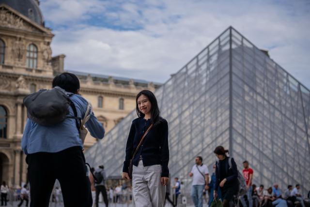 (261004) -- PARIS, Oct. 4, 2026 (Xinhua) -- A Chinese tourist poses for photos in front of the Louvre Museum in Paris, France, on Oct. 3, 2026. Paris has witnessed a large number of Chinese tourists who have chosen outbound trips during China's National Day holiday. (Photo by Aurelien Morissard/Xinhua)