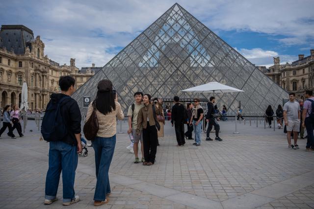 (261004) -- PARIS, Oct. 4, 2026 (Xinhua) -- Chinese tourists pose for photos in front of the Louvre Museum in Paris, France, on Oct. 3, 2026. Paris has witnessed a large number of Chinese tourists who have chosen outbound trips during China's National Day holiday. (Photo by Aurelien Morissard/Xinhua)