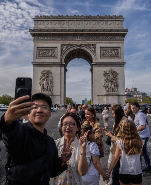 (261004) -- PARIS, Oct. 4, 2026 (Xinhua) -- Chinese tourists take a selfie in front of Arc de Triomphe in Paris, France, on Oct. 3, 2026. Paris has witnessed a large number of Chinese tourists who have chosen outbound trips during China's National Day holiday. (Photo by Aurelien Morissard/Xinhua)