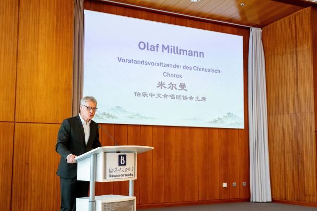 (261004) -- ESSEN, Oct. 4, 2026 (Xinhua) -- Olaf Millmann, chairman of the Burg Chinese Chorus association, speaks during a youth exchange concert in Essen, Germany, Oct. 3, 2026. Chinese and German students took the stage together on Saturday in the western German city of Essen for a youth exchange concert aimed at fostering cultural understanding and friendship through music.
   TO GO WITH "Chinese, German youth build ties through music at exchange concert" (Germany's Burg Chinese Chorus/Handout via Xinhua)