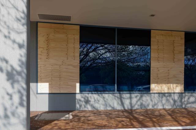 (261004) -- CANBERRA, Oct. 4, 2026 (Xinhua) -- Wooden boards are nailed over damaged windows of a government building in Canberra, Australia, on Oct. 4, 2026. Australian police said on Sunday they are investigating damage to two government buildings in Canberra after ball bearings were allegedly used to strike windows at the properties.
   TO GO WITH "Australian police investigate damage to gov't buildings in Canberra" (Photo by Chu Chen/Xinhua)