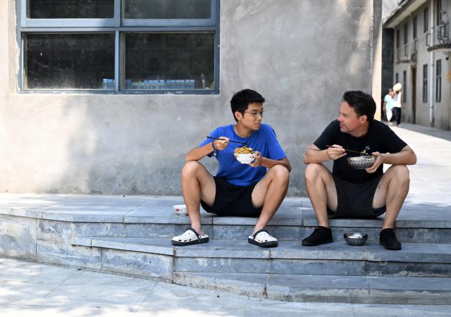 (261004) -- WENXIAN, Oct. 4, 2026 (Xinhua) -- Joseph Dauey (R), a Taijiquan enthusiast from Britain, has lunch in Chenjiagou Village of Wenxian County, central China's Henan Province, Aug. 26, 2026. Social media users in the West have recently embraced "Chinamaxxing," in which young people show interest in aspects of Chinese daily life.
   Taijiquan, a kind of traditional martial arts, was born in the mid-17th century in Chenjiagou Village. Rooted in Chinese philosophy, traditional medicine and martial arts, Taijiquan has evolved into a wide range of styles and is now practiced in more than 180 countries and regions. For foreign visitors, Chenjiagou is naturally one of the best spots to experience the "Chinamaxxing" trend. The small village offers a tranquil and comfortable living environment which lets visitors get away from the busy pace of city life and immerse themselves in traditional Chinese culture. (Xinhua/Li Jianan)