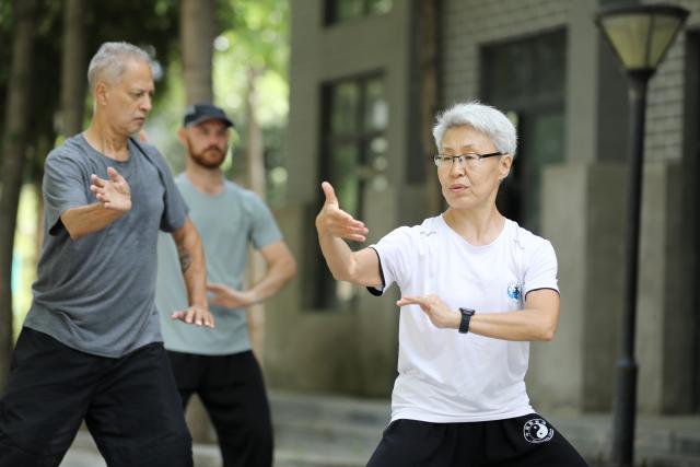 (261004) -- WENXIAN, Oct. 4, 2026 (Xinhua) -- Svetlana Kobiakova (R), a Russian Taijiquan coach, leads students to practice Taijiquan at a Taijiquan school in Chenjiagou Village of Wenxian County, central China's Henan Province, May 19, 2026. Social media users in the West have recently embraced "Chinamaxxing," in which young people show interest in aspects of Chinese daily life.
   Taijiquan, a kind of traditional martial arts, was born in the mid-17th century in Chenjiagou Village. Rooted in Chinese philosophy, traditional medicine and martial arts, Taijiquan has evolved into a wide range of styles and is now practiced in more than 180 countries and regions. For foreign visitors, Chenjiagou is naturally one of the best spots to experience the "Chinamaxxing" trend. The small village offers a tranquil and comfortable living environment which lets visitors get away from the busy pace of city life and immerse themselves in traditional Chinese culture. (Photo by Xu Hongxing/Xinhua)