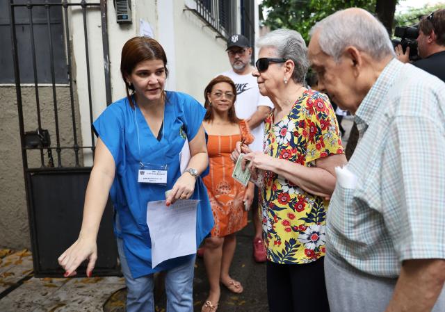 (261004) -- BRASILIA, Oct. 4, 2026 (Xinhua) -- A staff member guides voters at a polling station in Rio de Janeiro, Brazil, Oct. 4, 2026. Voting in the first round of Brazil's 2026 presidential election officially began at 8 a.m. (1100 GMT) on Sunday, with polling stations across the country scheduled to close at 5 p.m. (0800 GMT).
   Initial results are expected to be announced within a few hours after the polls close. (Xinhua/Jin Haoyuan)