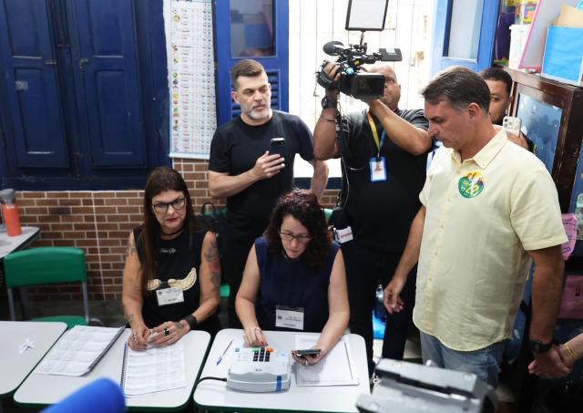 (261004) -- BRASILIA, Oct. 4, 2026 (Xinhua) -- Flavio Bolsonaro (1st R), presidential candidate of Brazil's Liberal Party, verifies his identity at a polling station in Rio de Janeiro, Brazil, Oct. 4, 2026. Voting in the first round of Brazil's 2026 presidential election officially began at 8 a.m. (1100 GMT) on Sunday, with polling stations across the country scheduled to close at 5 p.m. (0800 GMT).
   Initial results are expected to be announced within a few hours after the polls close. (Xinhua/Jin Haoyuan)