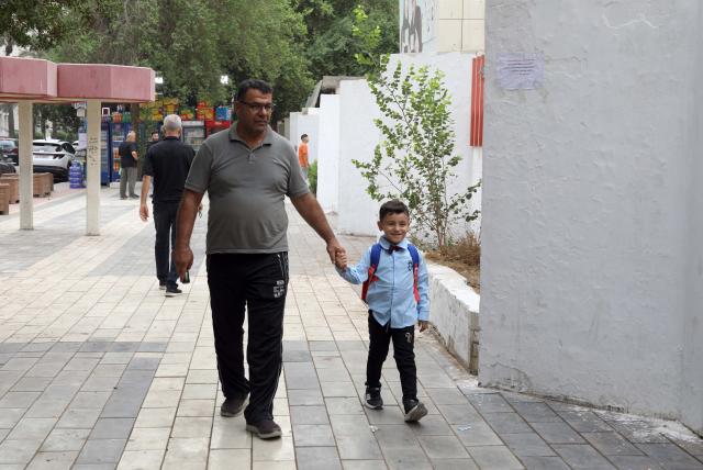 (261004) -- BAGHDAD, Oct. 4, 2026 (Xinhua) -- A boy goes to school with his father on the first day of new academic year in Baghdad, Iraq, on Oct. 4, 2026. The new academic year officially began in schools across Iraq on Sunday. (Xinhua/Khalil Dawood)