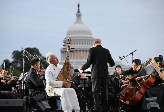 (261004) -- WASHINGTON, Oct. 4, 2026 (Xinhua) -- Chinese five-string pipa virtuoso Fang Jinlong performs with Manhattan Philharmonic during "Future Resonance -- ShanghaiEye Night" in Washington, D.C., the United States, on Oct. 3, 2026. The Shanghai-themed cultural exchange event was held here on Saturday, bringing a taste of Shanghai to the United States. The event was also part of the "Shanghai Let's Meet" city promotion initiative and a broader series of China-U.S. people-to-people exchanges. (Xinhua/Li Rui)