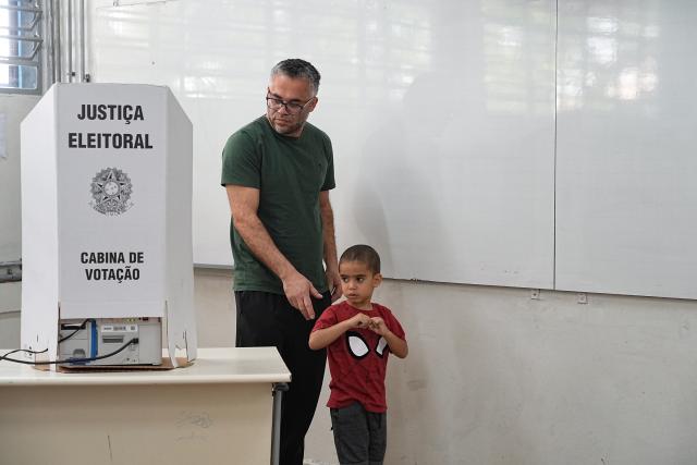 (261004) -- SAO PAULO, Oct. 4, 2026 (Xinhua) -- A voter is seen with his child after casting his ballot at a polling station in Sao Bernardo do Campo, Sao Paulo state, Brazil, Oct. 4, 2026. Voting in the first round of Brazil's 2026 presidential election officially began at 8 a.m. (1100 GMT) on Sunday, with polling stations across the country scheduled to close at 5 p.m. (0800 GMT). Initial results are expected to be announced within a few hours after the polls close. (Photo by Paulo Lopes/Xinhua)