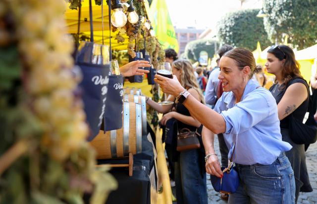 (261005) -- MARINO, Oct. 5, 2026 (Xinhua) -- A customer buys a glass of wine at a wine stand during the Grape Festival of Marino 2026 in Marino, Italy, Oct. 4, 2026. (Xinhua/Wang Kaiyan)