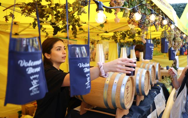 (261005) -- MARINO, Oct. 5, 2026 (Xinhua) -- A vendor gives a cup of wine to a customer during the Grape Festival of Marino 2026 in Marino, Italy, Oct. 4, 2026. (Xinhua/Wang Kaiyan)