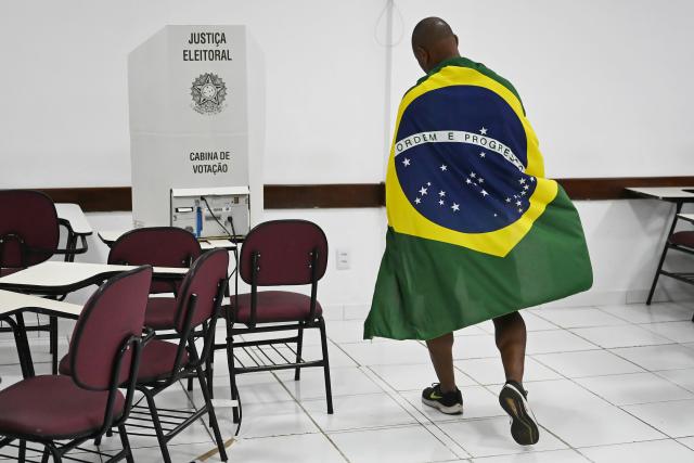 (261005) -- BRASILIA, Oct. 5, 2026 (Xinhua) -- A voter draped in a national flag is pictured at a polling station in Brasilia, Brazil, Oct. 4, 2026. (Photo by Lucio Tavora/Xinhua)
