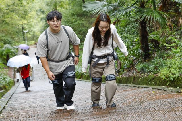 (261005) -- HUANGSHAN, Oct. 5, 2026 (Xinhua) -- Tourists wearing exoskeleton robots hike in the Qiyun Mountain scenic area of Xiuning County, Huangshan City, east China's Anhui Province, Oct. 2, 2026.
  The Qiyun Mountain scenic area offers exoskeleton robot rentals during the National Day holiday to help visitors hike with less effort. 
  The lightweight, easy-to-use devices sense body movements, providing uphill assistance and downhill cushioning to protect knees and reduce leg strain. 
  With a growing number of hikers in recent years, the area now offers over 20 such robots, using technology to deliver a smarter mountain climbing experience. (Photo by Shi Yalei/Xinhua)