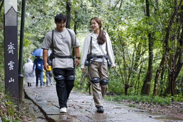 (261005) -- HUANGSHAN, Oct. 5, 2026 (Xinhua) -- Tourists wearing exoskeleton robots hike in the Qiyun Mountain scenic area of Xiuning County, Huangshan City, east China's Anhui Province, Oct. 2, 2026.
  The Qiyun Mountain scenic area offers exoskeleton robot rentals during the National Day holiday to help visitors hike with less effort. 
  The lightweight, easy-to-use devices sense body movements, providing uphill assistance and downhill cushioning to protect knees and reduce leg strain. 
  With a growing number of hikers in recent years, the area now offers over 20 such robots, using technology to deliver a smarter mountain climbing experience. (Photo by Shi Yalei/Xinhua)