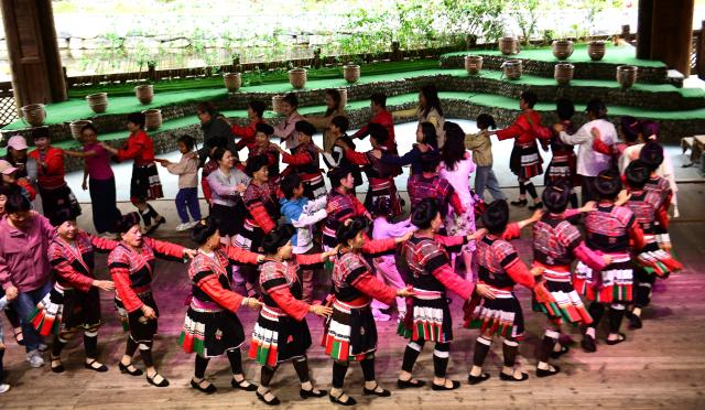 (261005) -- BEIJING, Oct. 5, 2026 (Xinhua) -- Tourists dance with local women of the Yao ethnic group in Longsheng County of Guilin City, south China's Guangxi Zhuang Autonomous Region, Oct. 5, 2026. Large numbers of visitors have flocked to rural areas across China during the National Day holiday. (Photo by Pan Zhixiang/Xinhua)