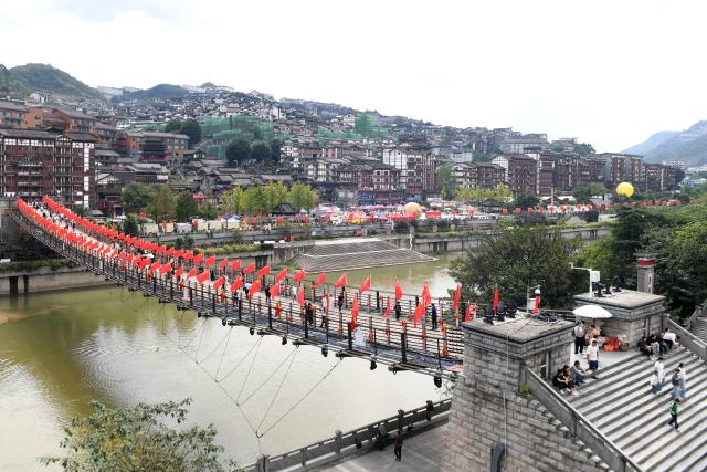 (261005) -- BEIJING, Oct. 5, 2026 (Xinhua) -- Tourists visit an iron-chain bridge in Maotai Township of Renhuai City, southwest China's Guizhou Province, Oct. 5, 2026. Large numbers of visitors have flocked to rural areas across China during the National Day holiday. (Photo by Chen Yong/Xinhua)