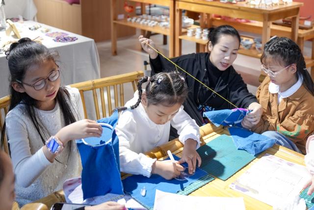 (261005) -- BEIJING, Oct. 5, 2026 (Xinhua) -- Children experience embroidery in Anji County of Huzhou, east China's Zhejiang Province, Oct. 5, 2026. Large numbers of visitors have flocked to rural areas across China during the National Day holiday. (Photo by Pan Xuekang/Xinhua)