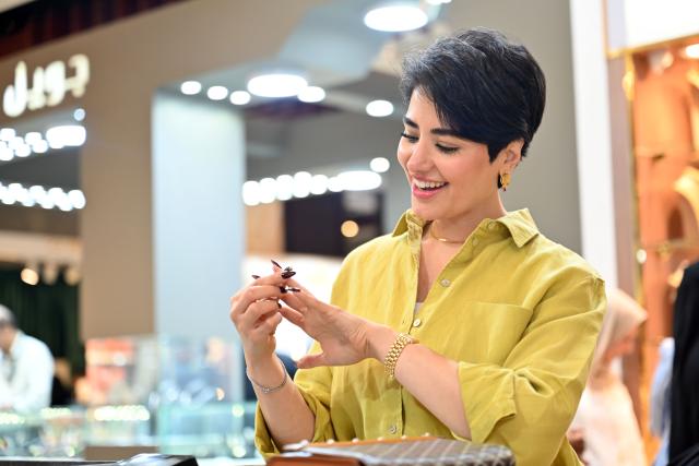 (261005) -- HAWALLI GOVERNORATE, Oct. 5, 2026 (Xinhua) -- A woman views jewelry on display at the Thameen Expo in Hawalli Governorate, Kuwait, Oct. 5, 2026. The Thameen Expo, featuring jewelry and luxury products, opened Monday at the Kuwait International Fairground in Hawalli Governorate, Kuwait. The exhibition will run through Oct. 10. (Photo by Asad/Xinhua)