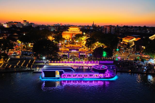 (261006) -- BEIJING, Oct. 6, 2026 (Xinhua) -- A drone photo taken on Oct. 5, 2026 shows people cruising a scenic area in Yangzhou, east China's Jiangsu Province. During the National Day holiday, night tours were launched across China to create diversified consumption scenes. (Photo by Meng Delong/Xinhua)
