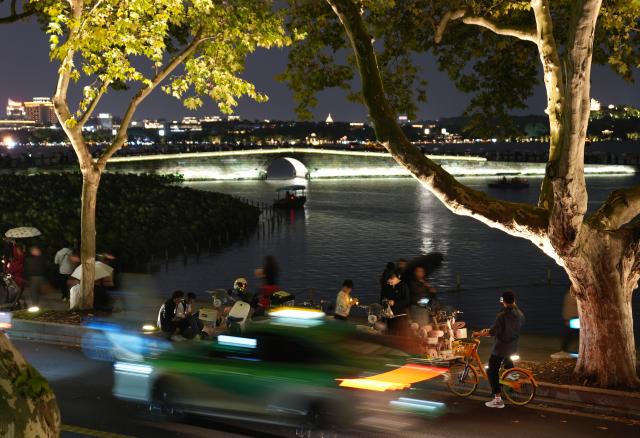 (261006) -- BEIJING, Oct. 6, 2026 (Xinhua) -- People tour near the West Lake scenic spot in Hangzhou, east China's Zhejiang Province, Oct. 5, 2026. During the National Day holiday, night tours were launched across China to create diversified consumption scenes. (Xinhua/Han Chuanhao)