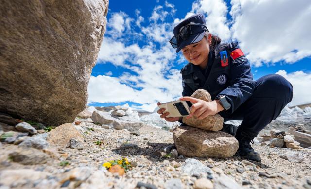 (261006) -- LHASA, Oct. 6, 2026 (Xinhua) -- A police officer of the Pumaqangtang border police station takes photos of flowers along the patrol route in Shannan, southwest China's Xizang Autonomous Region, Aug. 19, 2026. Pumaqangtang, China's highest township, has an average altitude of 5,373 meters, with oxygen levels less than a half of that at sea level.
   Here stands the Pumaqangtang border police station, the highest-altitude border police station in China. Police and auxiliary police officers here, with an average age of just over 30, hold their posts on the frigid, oxygen-thin plateau. (Xinhua/Tenzin Nyida)