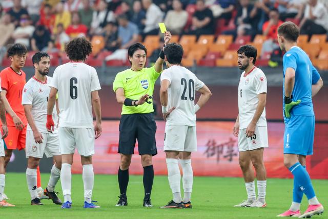 (261006) -- CHONGQING, Oct. 6, 2026 (Xinhua) -- The referee (4th L) gives a yellow card to Alijon Karomatullozoda (3rd R) of Tajikistan during the CFA Team China International Football Competitions Chongqing 2026 between China and Tajikistan in Chongqing, Oct. 6, 2026. (Xinhua/Huang Wei)