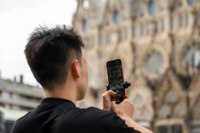 (261006) -- BARCELONA, Oct. 6, 2026 (Xinhua) -- A Chinese tourist takes photos in front of Sagrada Familia Basilica in Barcelona, Spain, Oct. 6, 2026. (Photo by Joan Gosa/Xinhua)