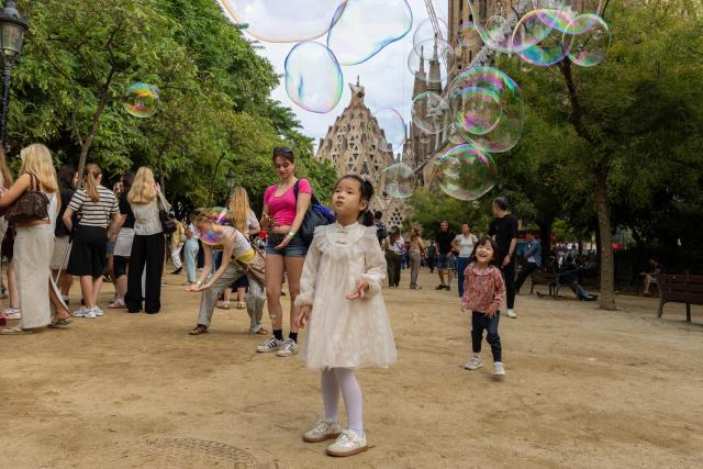 (261006) -- BARCELONA, Oct. 6, 2026 (Xinhua) -- Chinese tourists play with soap bubbles near the Sagrada Familia Basilica in Barcelona, Spain, Oct. 6, 2026. (Photo by Joan Gosa/Xinhua)