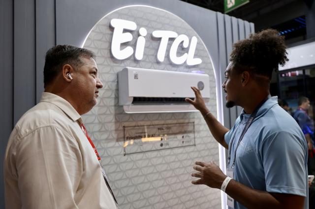 (261007) -- RIO DE JANEIRO, Oct. 7, 2026 (Xinhua) -- A staff member (R) introduces an air conditioner of TCL during the FEBRAVA Rio at the Riocentro convention and event center in Rio de Janeiro, Brazil, Oct. 6, 2026. The three-day FEBRAVA Rio (Portuguese short for International Fair of Refrigeration, Air Conditioning, Ventilation, Heating, Air and Water Treatment) kicked off here on Tuesday. Some Chinese brands showcased their latest products during the fair, drawing great attention from visitors. (Xinhua/Jin Haoyuan)