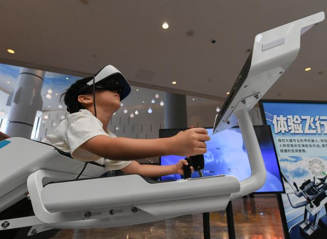 (261007) -- BEIJING, Oct. 7, 2026 (Xinhua) -- A child tries a simulated flight with a pair of VR glasses at a science and technology museum in Jinhua, east China's Zhejiang Province, Oct. 6, 2026. Advanced technologies such as exoskeleton devices, AI-powered glasses and robots have enabled diverse and dazzling experiences at tourist destinations across China during the National Day holiday. (Photo by Shi Kuanbing/Xinhua)