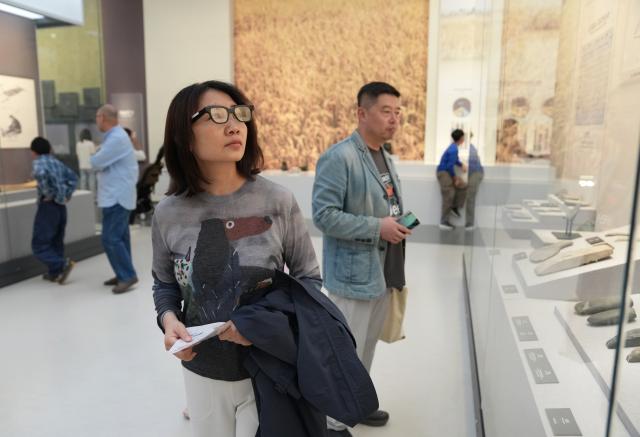 (261007) -- BEIJING, Oct. 7, 2026 (Xinhua) -- A citizen tries on AI glasses while visiting the Liangzhu Museum in Hangzhou, east China's Zhejiang Province, Oct. 6, 2026. Advanced technologies such as exoskeleton devices, AI-powered glasses and robots have enabled diverse and dazzling experiences at tourist destinations across China during the National Day holiday. (Xinhua/Han Chuanhao)