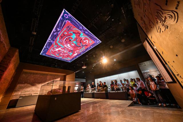 (261007) -- BEIJING, Oct. 7, 2026 (Xinhua) -- People watch an immersive 3D Mapping show at Shangqiu Museum in Shangqiu, central China's Henan Province, Oct. 7, 2026. Advanced technologies such as exoskeleton devices, AI-powered glasses and robots have enabled diverse and dazzling experiences at tourist destinations across China during the National Day holiday. (Photo by Li Heng/Xinhua)
